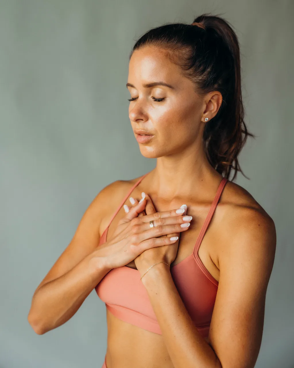 Portrait of Kelsey Rose with eyes closed, hands on chest