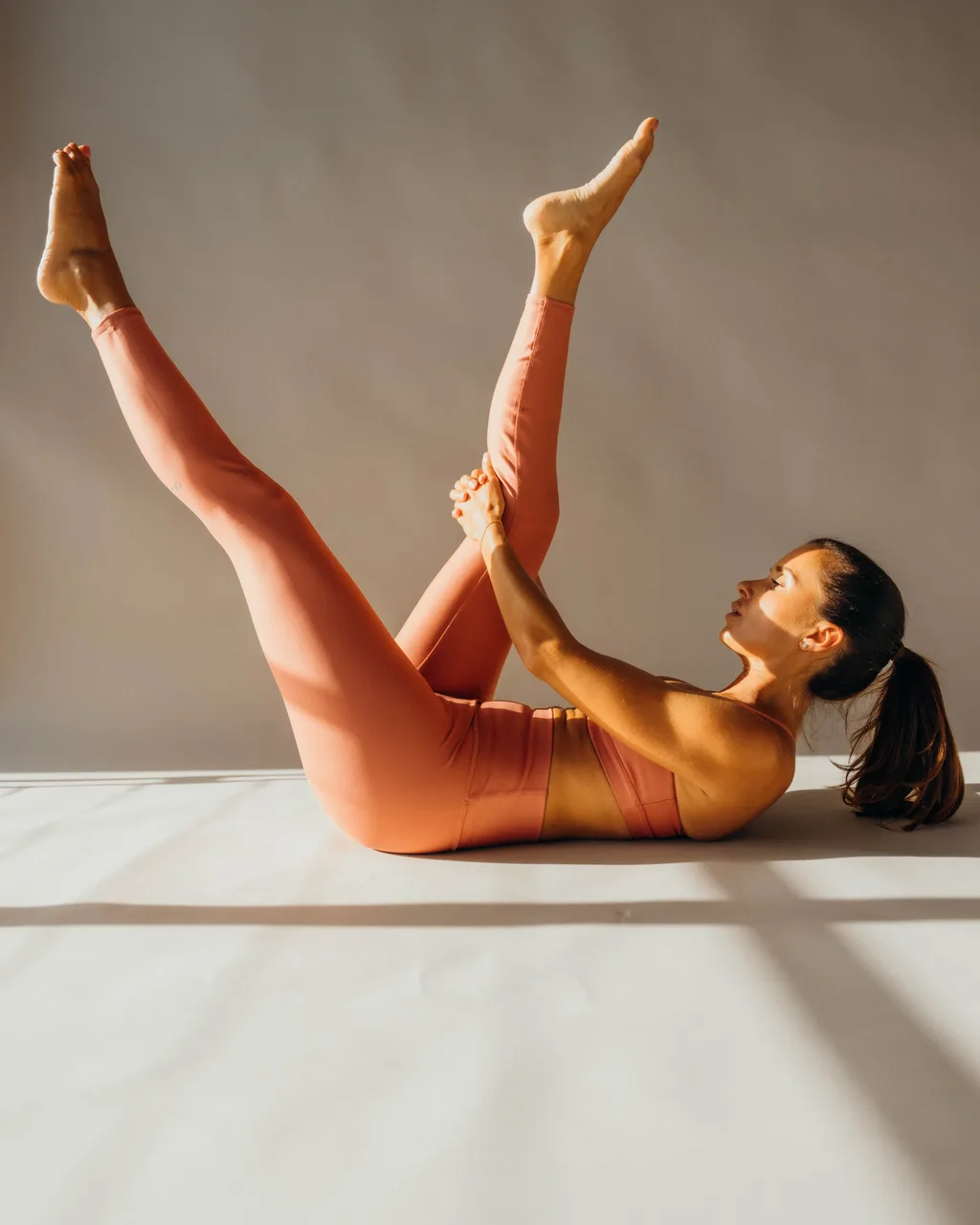 Kelsey Rose doing a leg raise in coral leggings