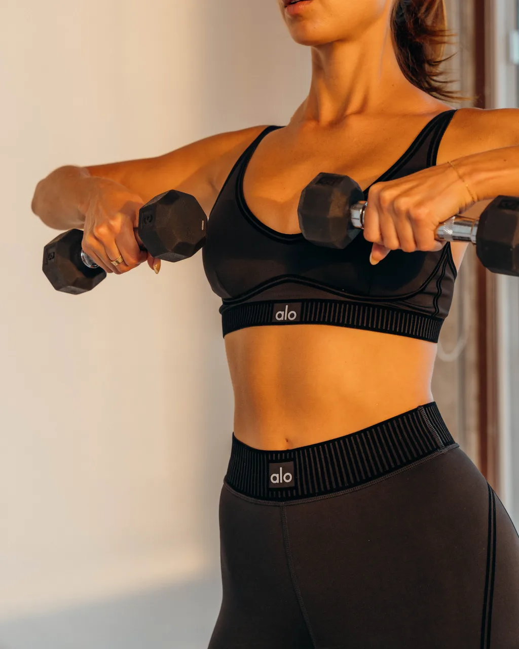 Kelsey Rose holding dumbbells in black activewear