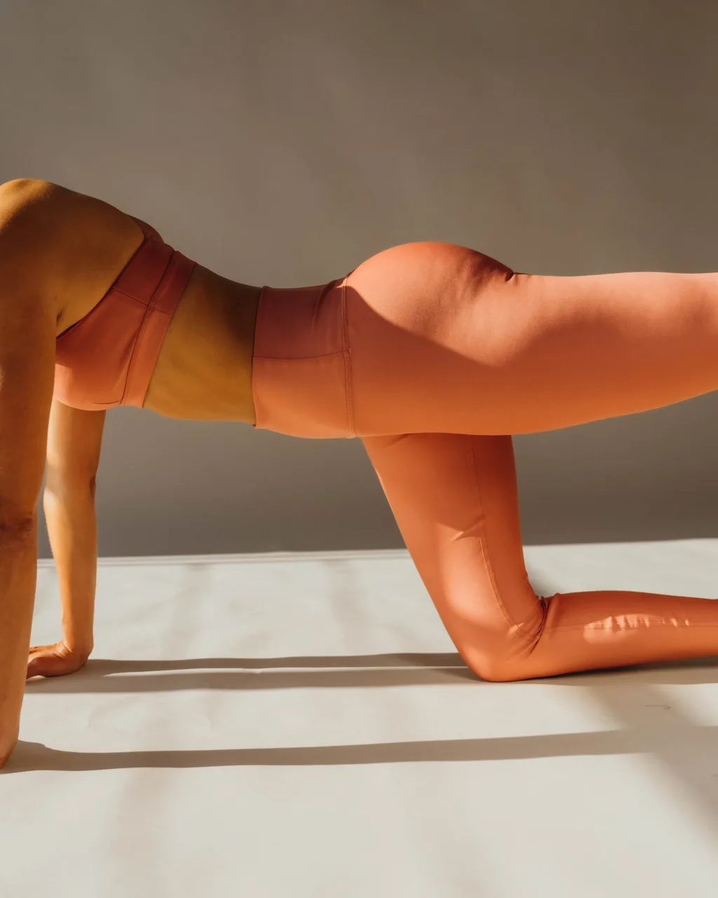 Kelsey Rose on all fours in coral leggings