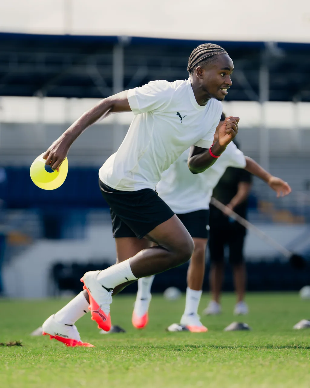 Young player sprinting through a cone drill in PUMA boots