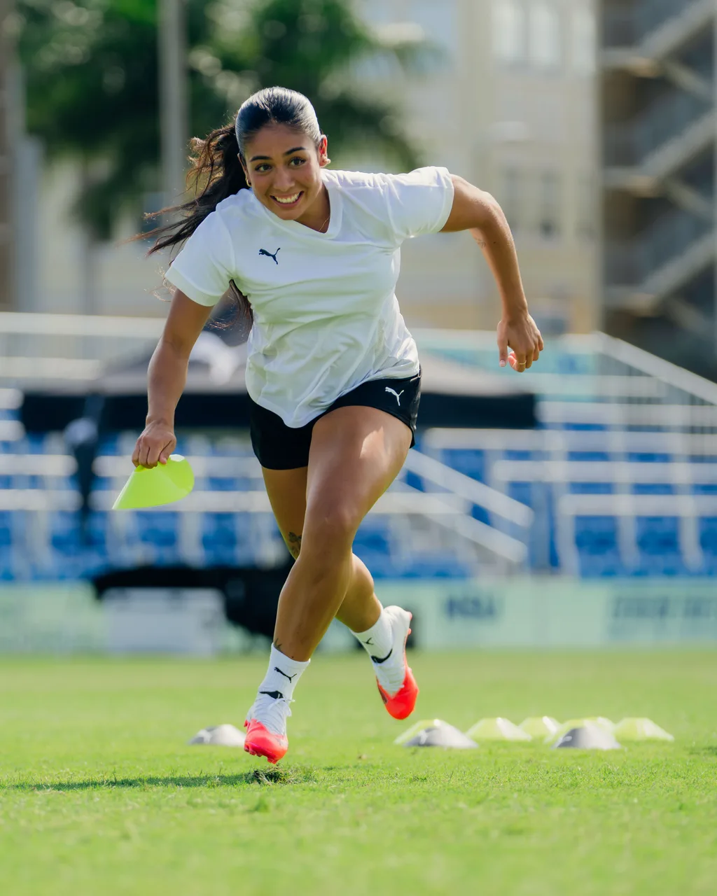Young player smiling as she sprints through a cone drill in PUMA boots
